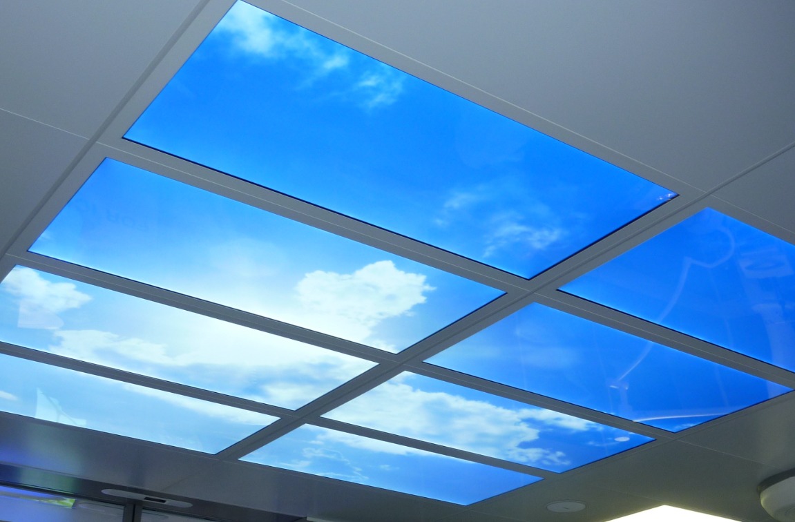 Lichtdecke mit blauem Himmel, weißen Wolken und Sonne als künstliches Oberlicht. Die LED Wolken-Decke ist in 8 Felder unterteilt, um den Eindruck eines echten Fensters zu verstärken.