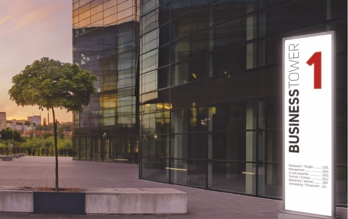 LED-Panel mit Aufschrift „Business Tower 1“ als Glasstele vor einem Bürogebäude