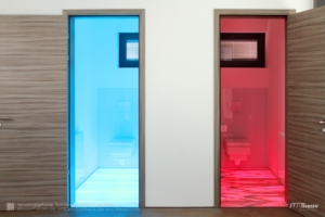 Zwei Toiletten mit LED-Bodenbeleuchtung: links blau beleuchteter Glas-Boden, rechts rot hinterleuchteter Marmor-Boden.