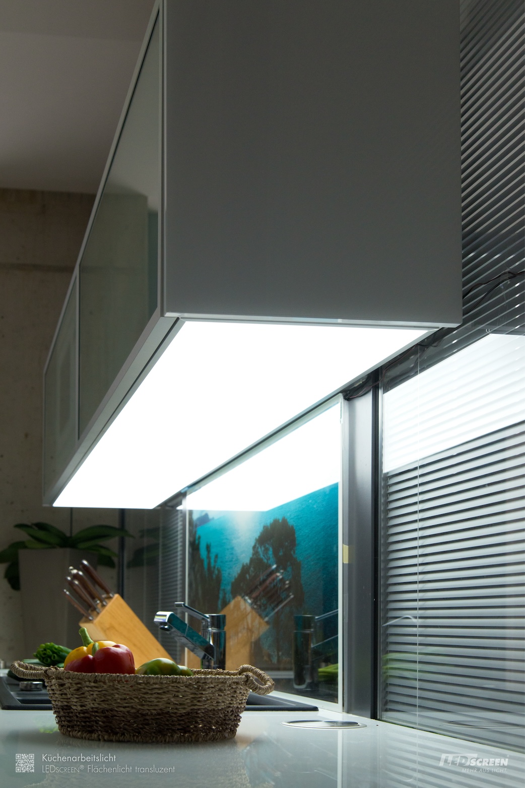 Beleuchtete Küchenrückwand aus Glas mit Motiv und darüber großflächige, weiße LED-Unterbauleuchte unter dem Hängeschrank zur Beleuchtung der Arbeitsfläche.