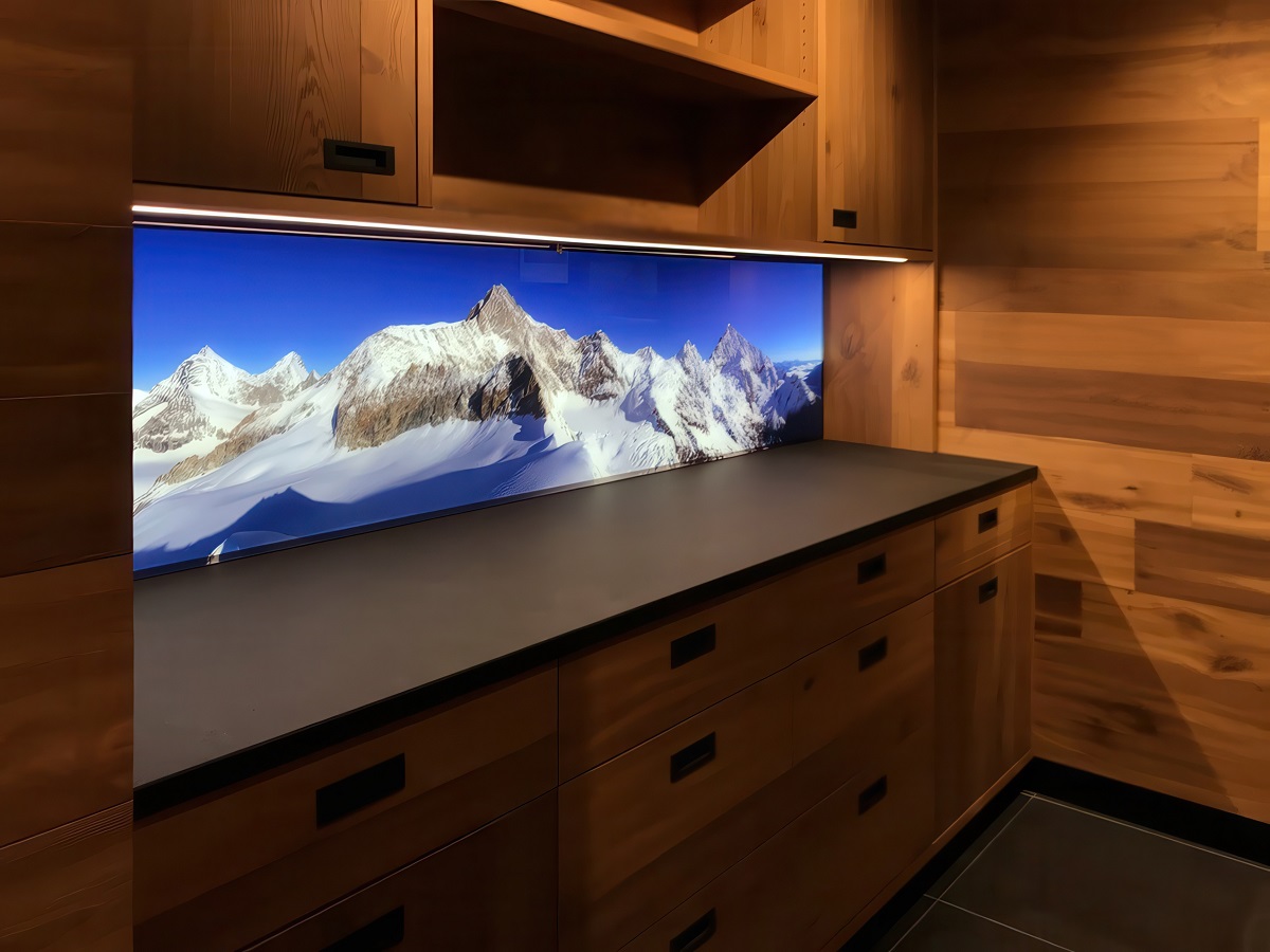 LED-beleuchtete Küchenrückwand aus Glas mit Motiv (schneebedeckte Berge) in einer modernen Küche aus Echtholz. Eine LED-Unterbauleuchte sorgt für noch mehr Licht.