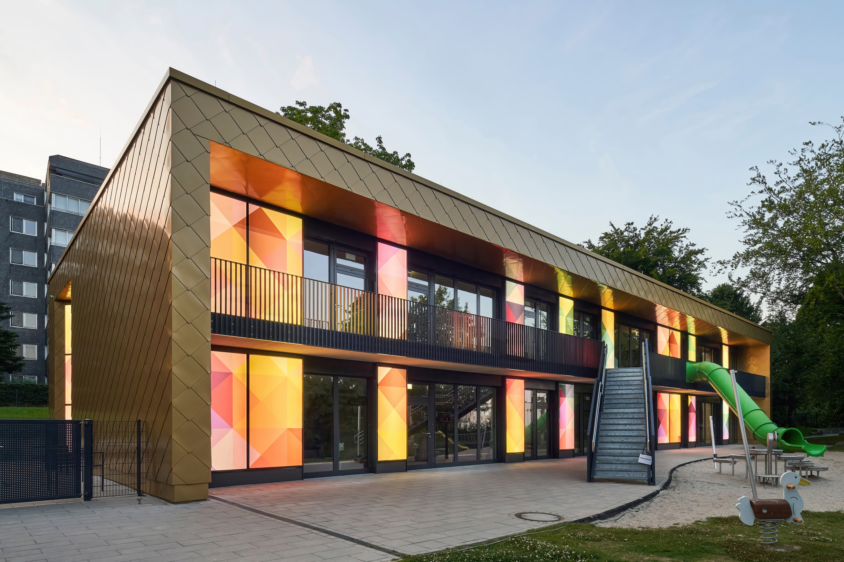 Die Fassade der Kita Tannenhof in Remscheid wird von mehreren bunten LED-Panels mit Vektor-Grafiken beleuchtet.