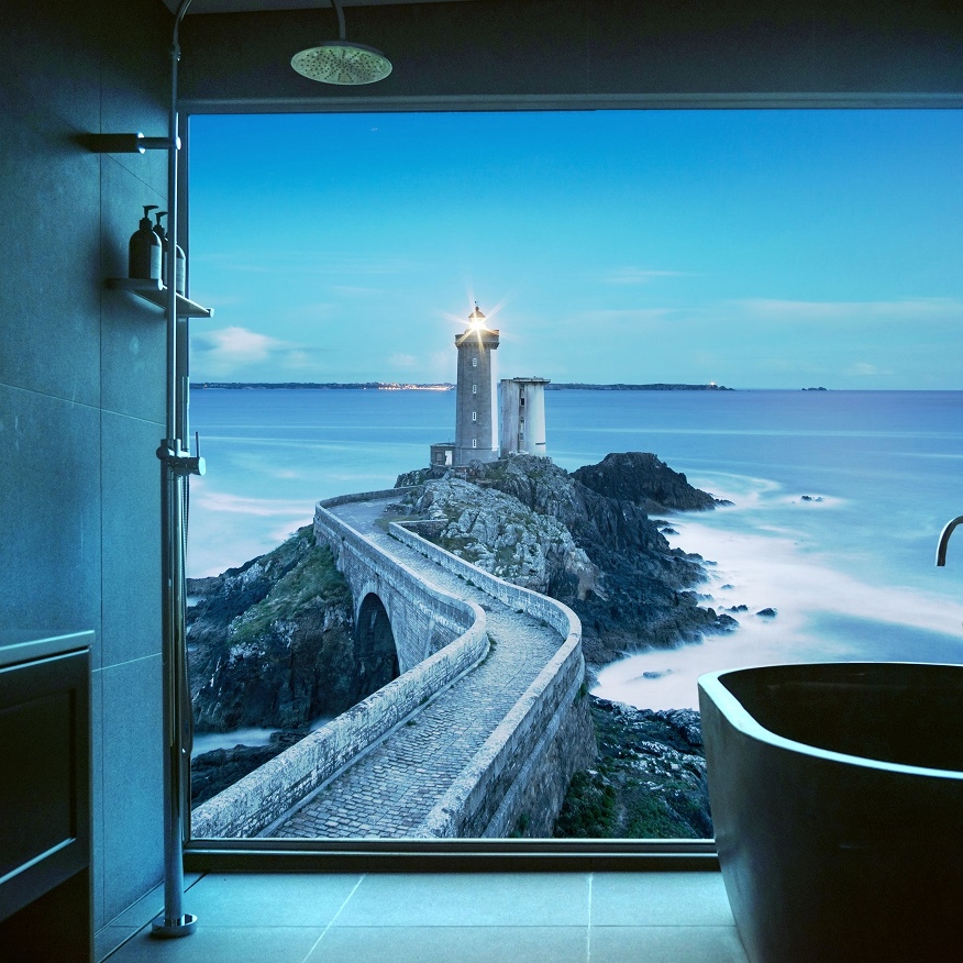 Graues Badezimmer, das von einer beleuchteten Duschrückwand beleuchtet wird. Das künstliche Fenster zeigt den Leuchtturm Petit Minou am Eingang zur Bucht von Brest (Rade de Brest) in der Gemeinde Plouzané in der Bretagne